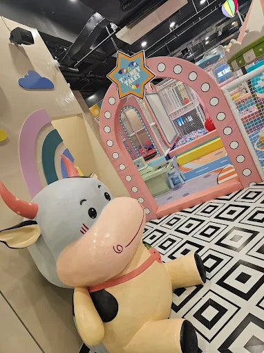 Indoor children’s play area featuring a large bull character, pastel rainbow walls, and colorful play structures at Tooney Tales Gurugram