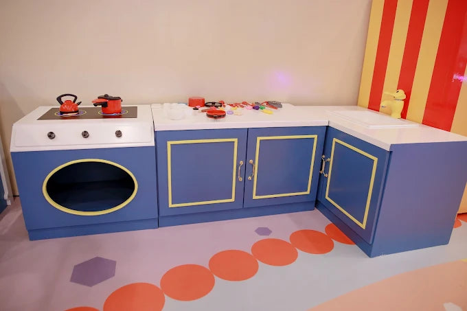 Kid’s play kitchen set with blue cabinets, toy stove, and colorful cookware in a playful indoor setting