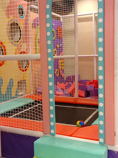 Indoor kids’ play zone with soft climbing blocks, padded platforms, and colorful netted walls for safe fun