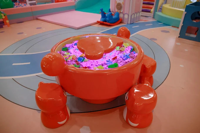 Round orange activity table with glowing colorful toys in a vibrant children’s play zone at Tooney Tales Gurugram
