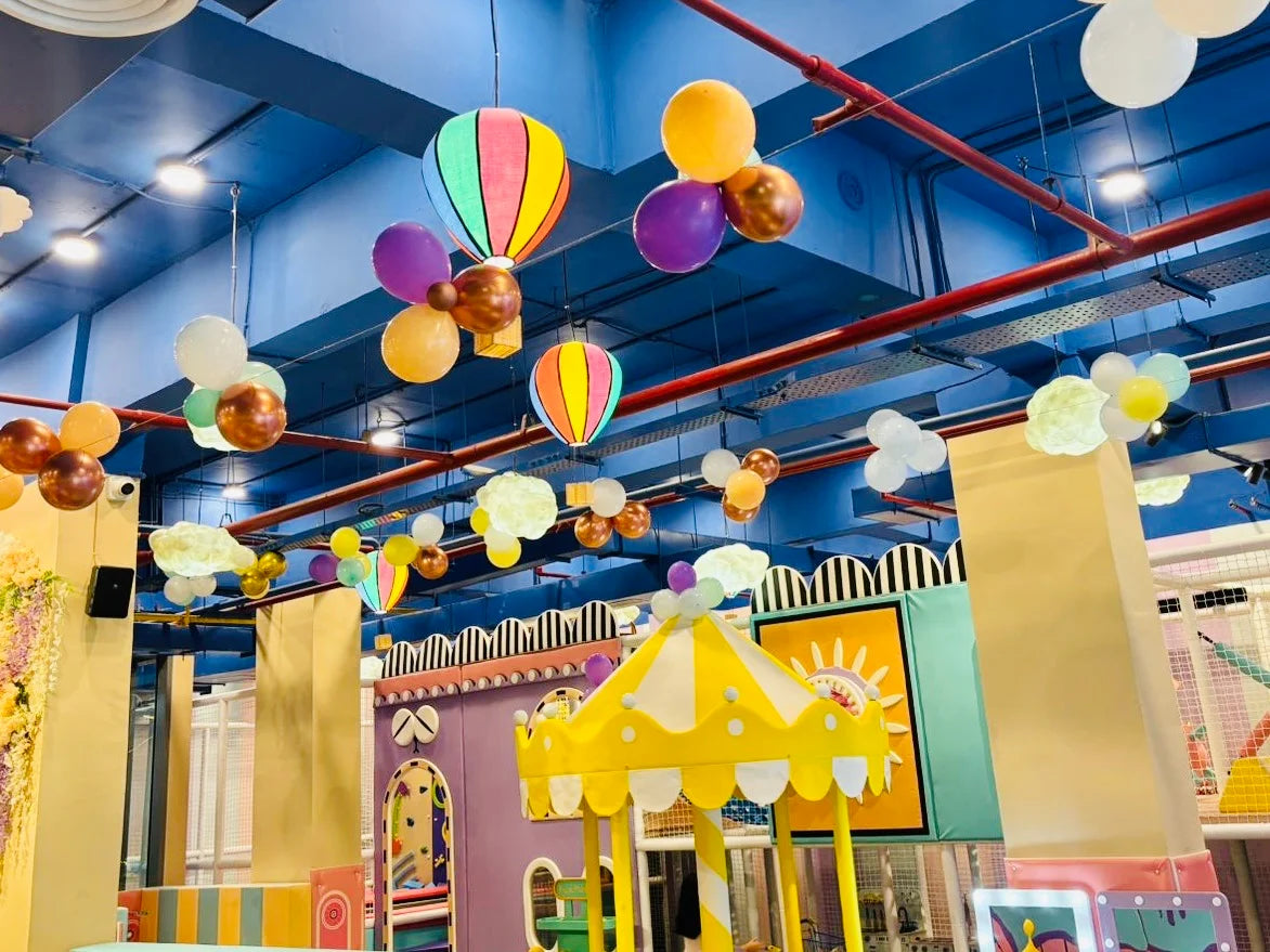 Colorful indoor playground with balloons and play structures.