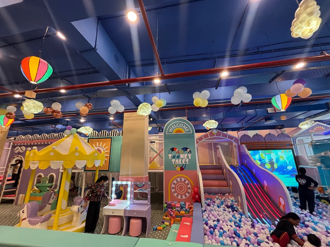 Children's play area with colorful slides, ball pit, and toys in a indoor playground.