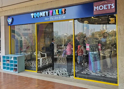 Front view of Tooney Tales indoor play area and café with glass doors and colorful signage at AIPL Joy Street Gurugram