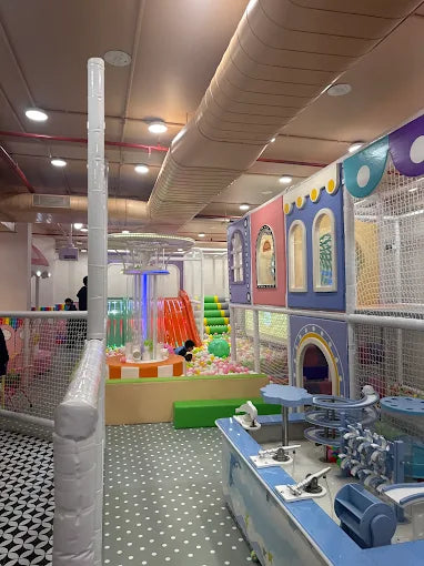 A colorful indoor playground with ball pits, slides, and play structures for children.