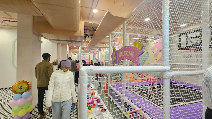 Children play in a colorful indoor playground with a "Welcome" sign.