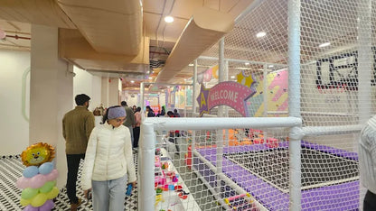 Children play in a colorful indoor playground with a "Welcome" sign.