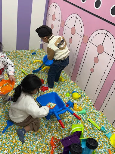 Children play with toys in a ball pit.