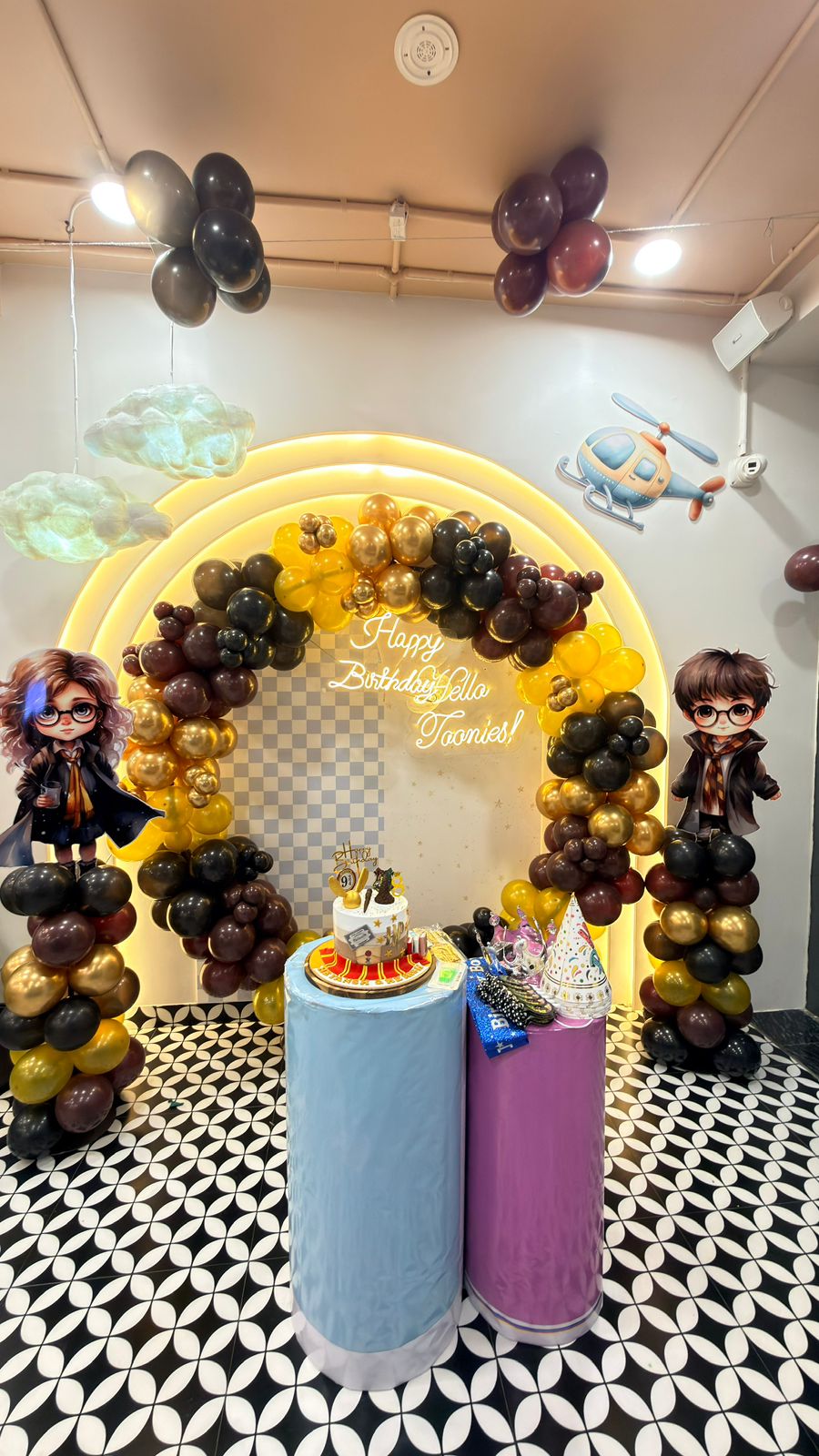 A Harry Potter-themed birthday party setup with balloons, a cake, and character cutouts.