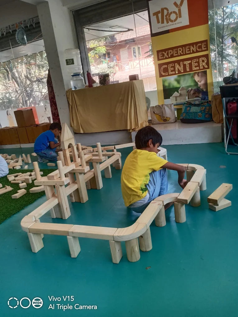 Children play with wooden blocks in an indoor play area.
