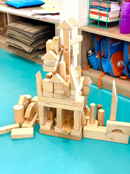 Children's wooden blocks are built into a castle on a blue mat.