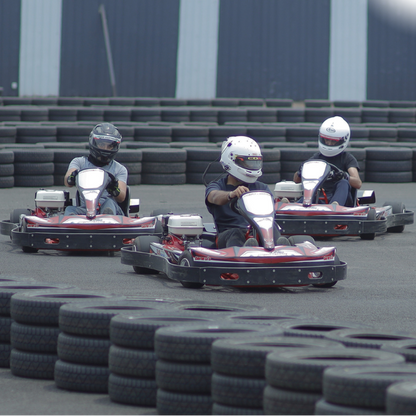 Three people in go-karts on a track with tires surrounding them.