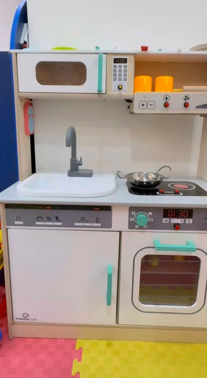 A child's toy kitchen with a microwave, sink, stove, and oven.