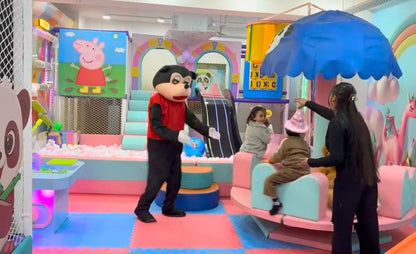 A mascot interacts with children in a colorful indoor playground.