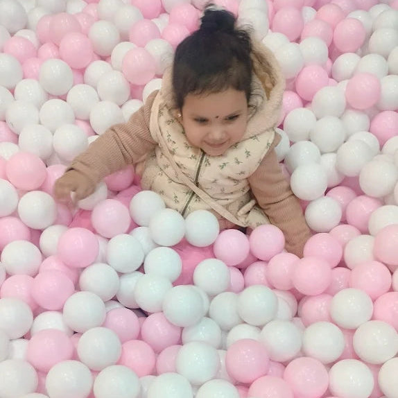 Child playing in a pit filled with pink and white balls