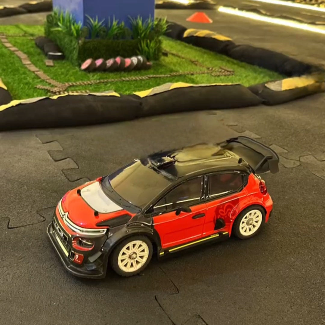 Model car on a miniature race track with grass and blue wall in the background