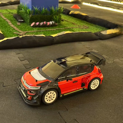 Model car on a miniature race track with grass and blue wall in the background