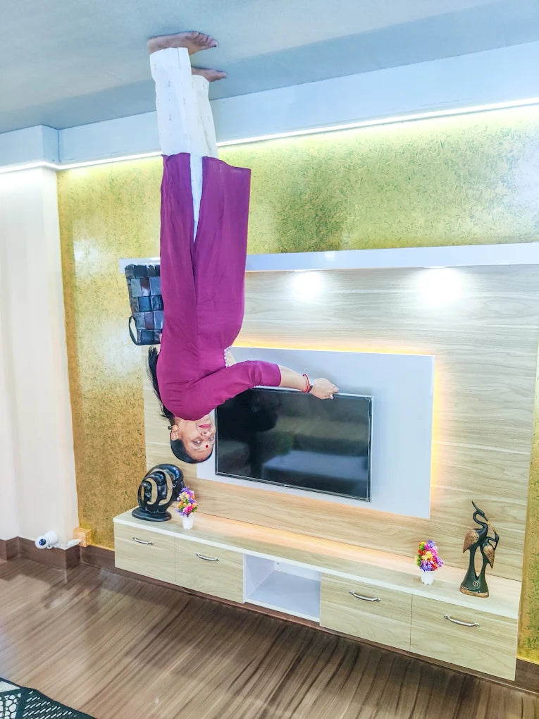 A woman is upside down on the ceiling, appearing to walk on it, in a room with a TV.