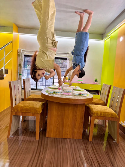 Two people are doing handstands over a dining table set with bowls.
