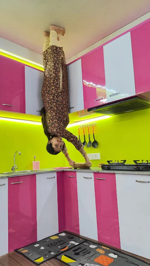A young woman is upside down in a kitchen, appearing to roll dough on the counter.