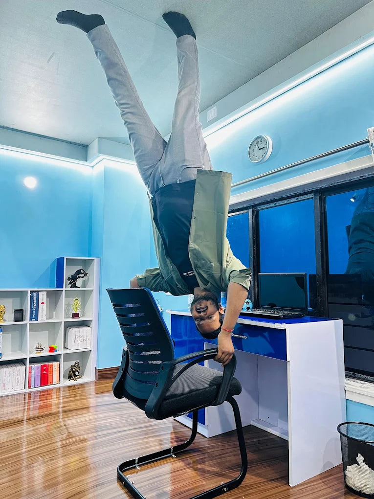 A young man performs a handstand on an office chair, with his feet touching the ceiling.