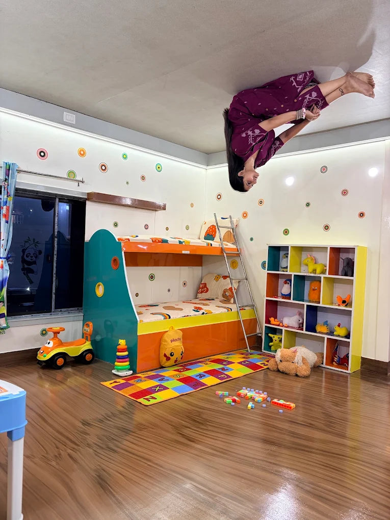 A young woman does a handstand on the ceiling of a colorful children's bedroom.