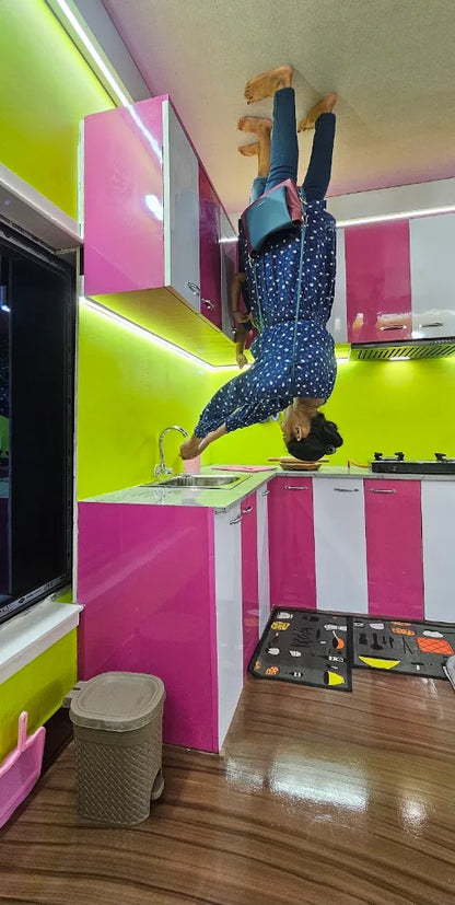 A person is upside down in an upside-down kitchen, appearing to wash their hands.
