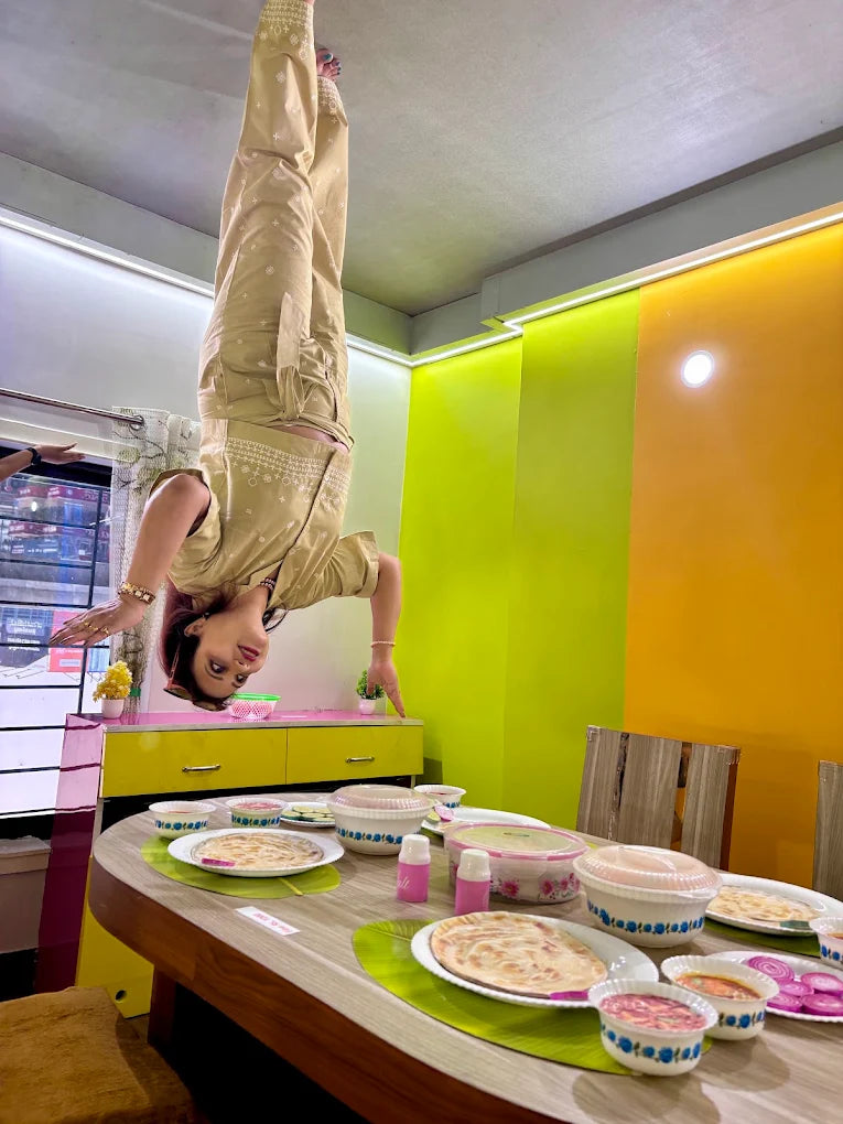 A woman is doing a handstand over a dining table set for a meal.