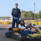 A man and woman stand by a go-kart on a track.