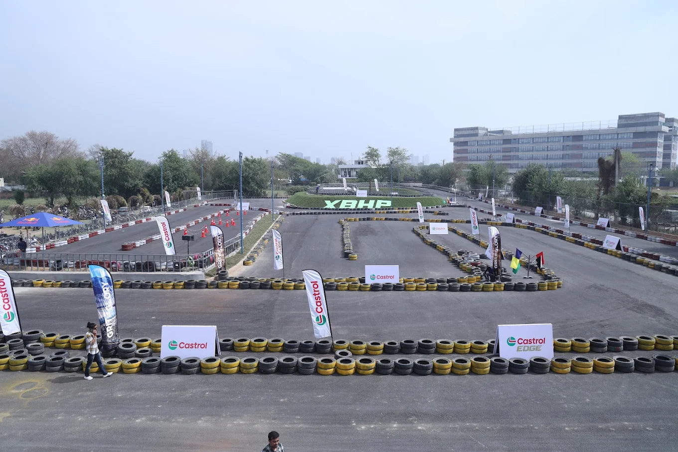 A go-kart track with tire barriers and Castrol banners, with a few young adults visible.