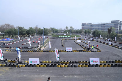 A go-kart track with tire barriers and Castrol banners, with a few young adults visible.
