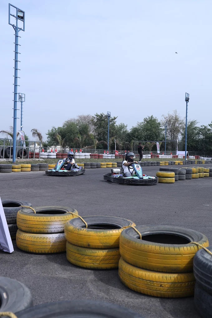 Two children race go-karts on a track lined with tires.