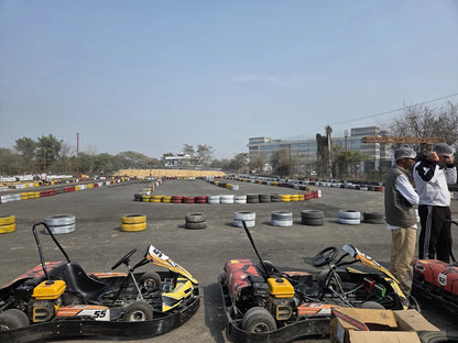Go-karts on a track with adults in the background.
