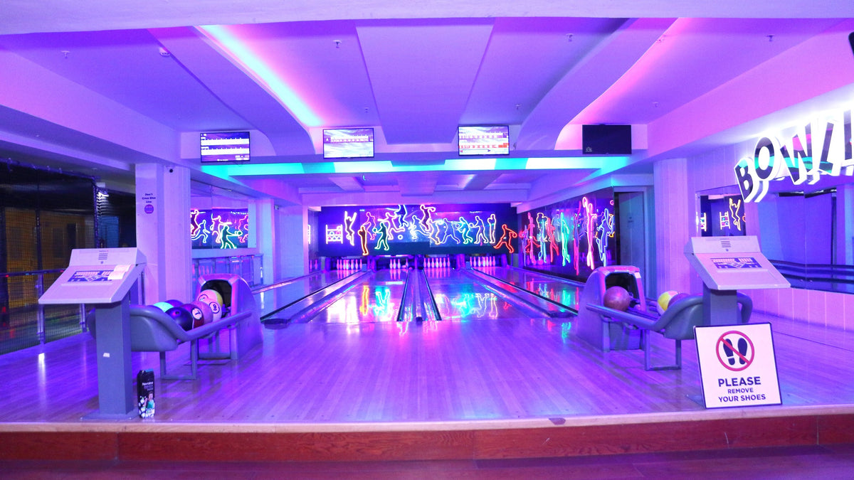 A brightly lit bowling alley with neon lights and bowling balls.