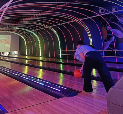 People bowling in a lane with digital scoreboards above