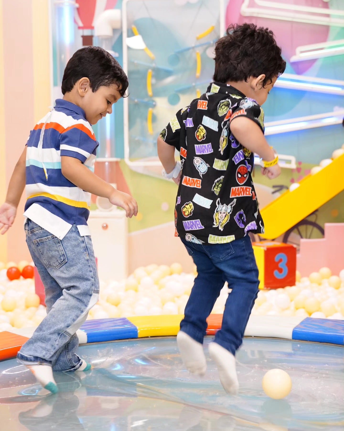 Two boys joyfully bouncing on a colorful trampoline surrounded by soft play balls at Walk to Wonderland Chhatarpur