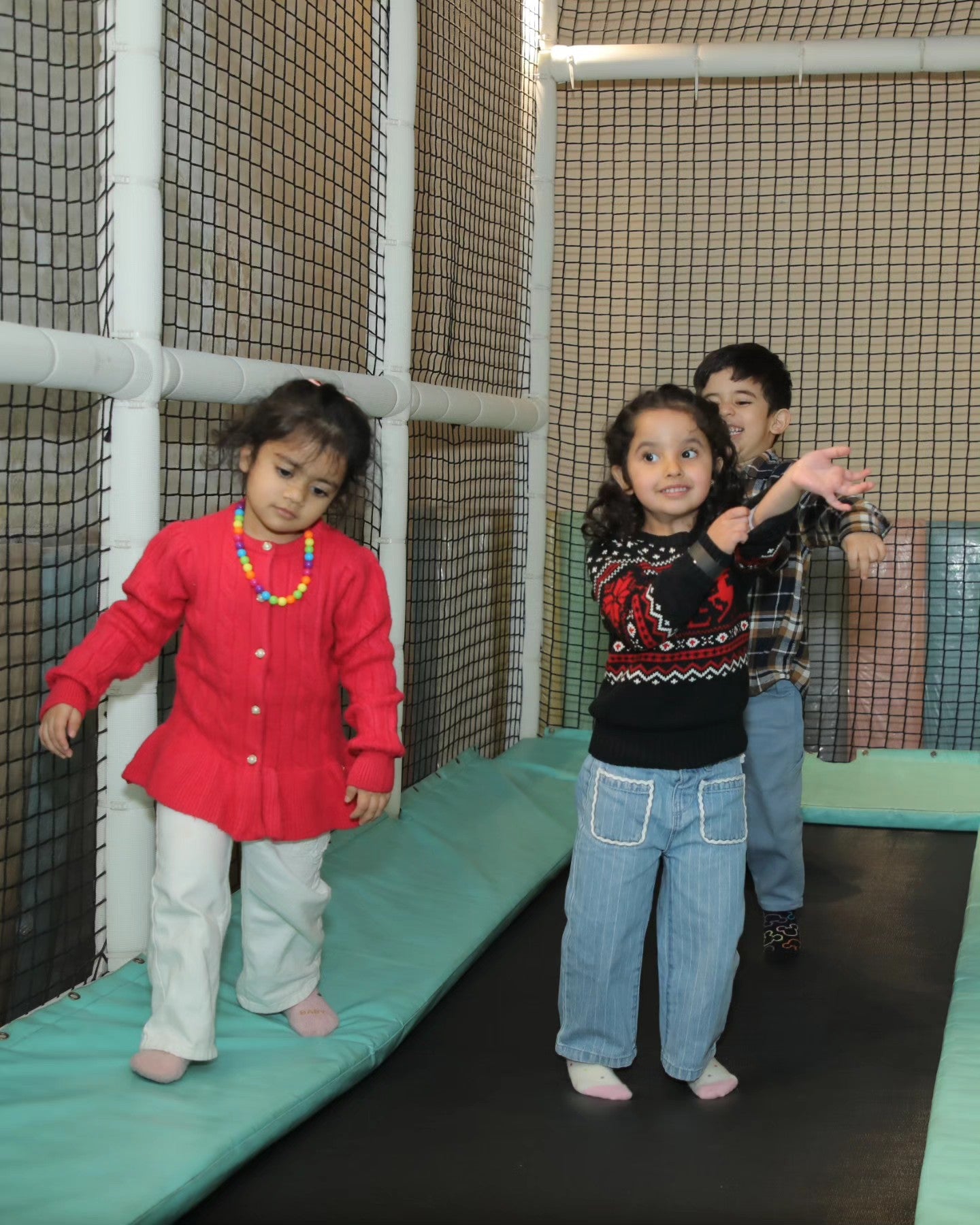 Three children enjoying a padded trampoline area enclosed by safety nets at Walk to Wonderland Chhatarpur New Delhi