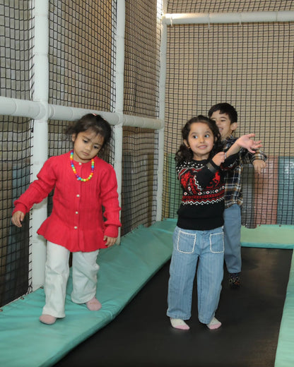 Three children enjoying a padded trampoline area enclosed by safety nets at Walk to Wonderland Chhatarpur New Delhi