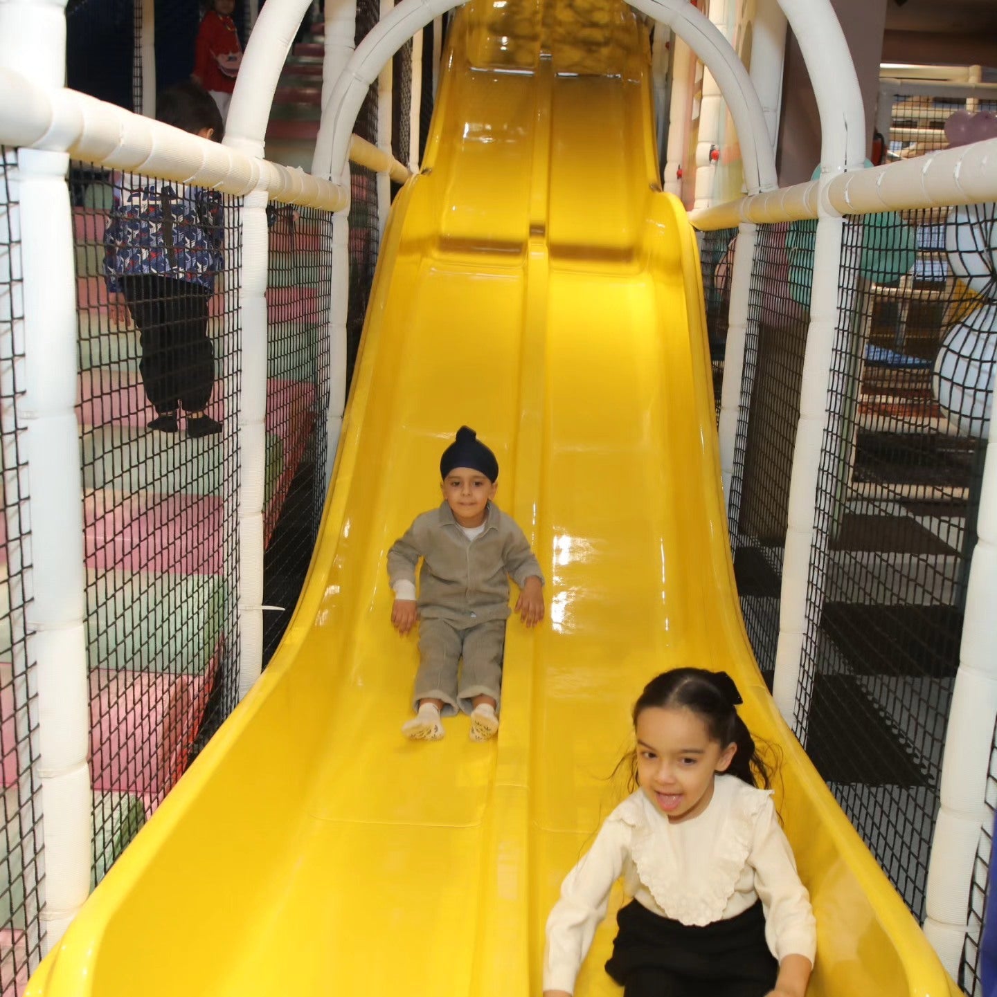 Two children enjoying a bright yellow slide inside Walk to Wonderland Indoor Play Area Chhatarpur New Delhi