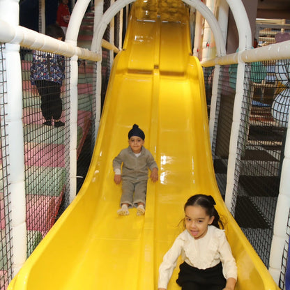 Two children enjoying a bright yellow slide inside Walk to Wonderland Indoor Play Area Chhatarpur New Delhi