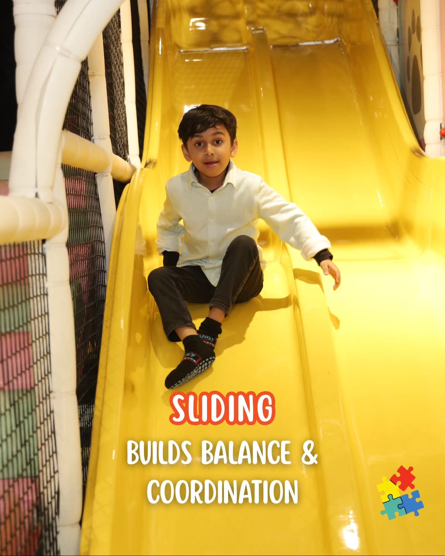 Young boy in white shirt sliding down a bright yellow slide inside Walk to Wonderland play area Chhatarpur