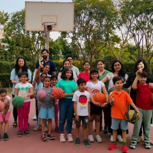 Group of children and adults with sports balls on a basketball court