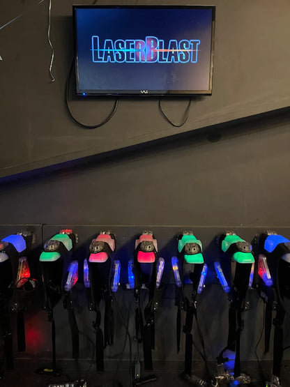 Laser tag vests and phasers are displayed on a wall below a "Laser Blast" sign.