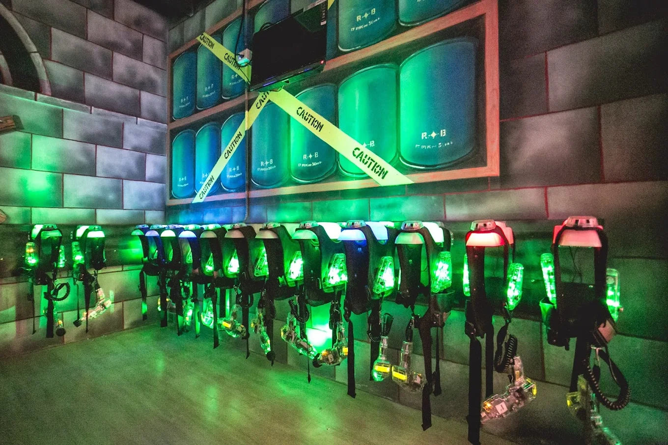 Laser tag vests and phasers are displayed in a dimly lit arena with green lighting.
