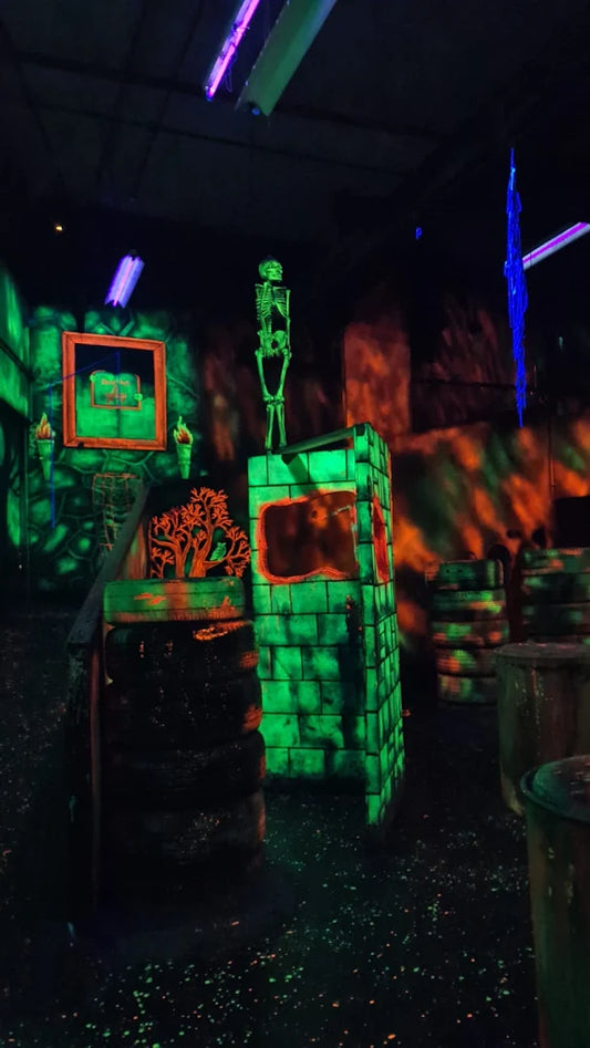 A spooky, neon-lit indoor arena with a skeleton decoration and brick-like structures.