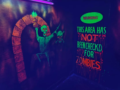 A neon mural in a dark room depicts skeletons and a warning sign about zombies.