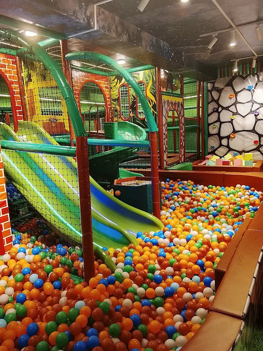A colorful ball pit with slides in a children's indoor playground.