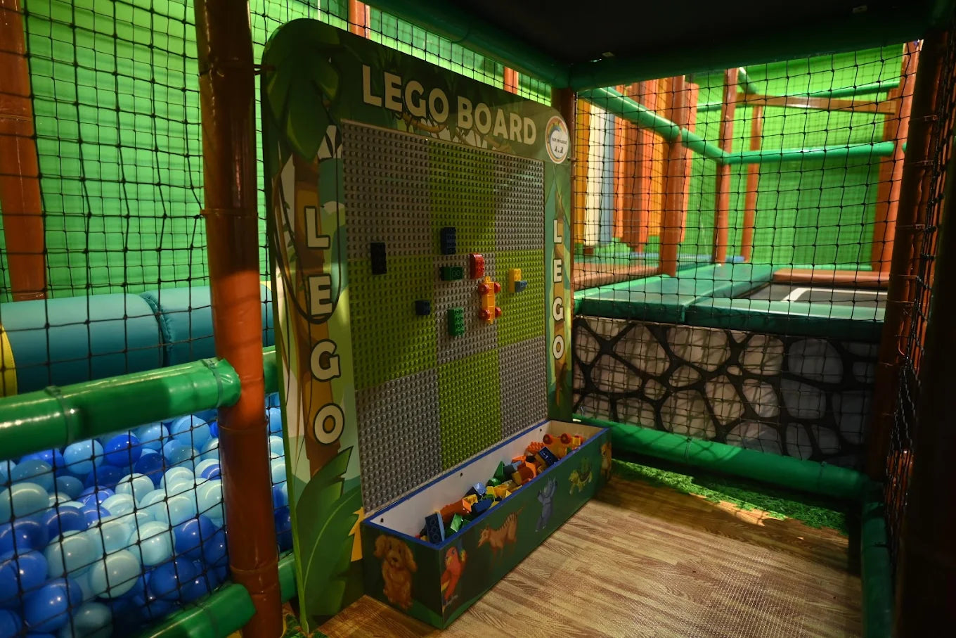 A children's indoor play area with a LEGO board, ball pit, and soft play structures.