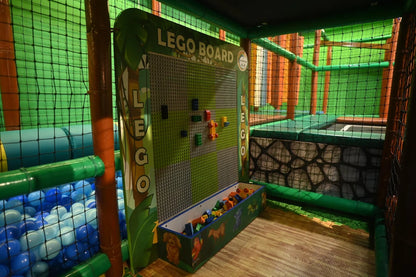 A children's indoor play area with a LEGO board, ball pit, and soft play structures.
