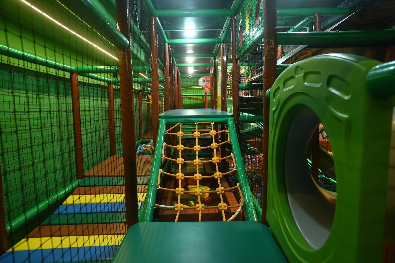 A colorful indoor playground with nets, slides, and a ball pit for children.