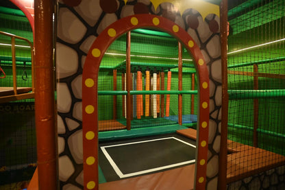 A colorful indoor playground with a trampoline and climbing structures for children.